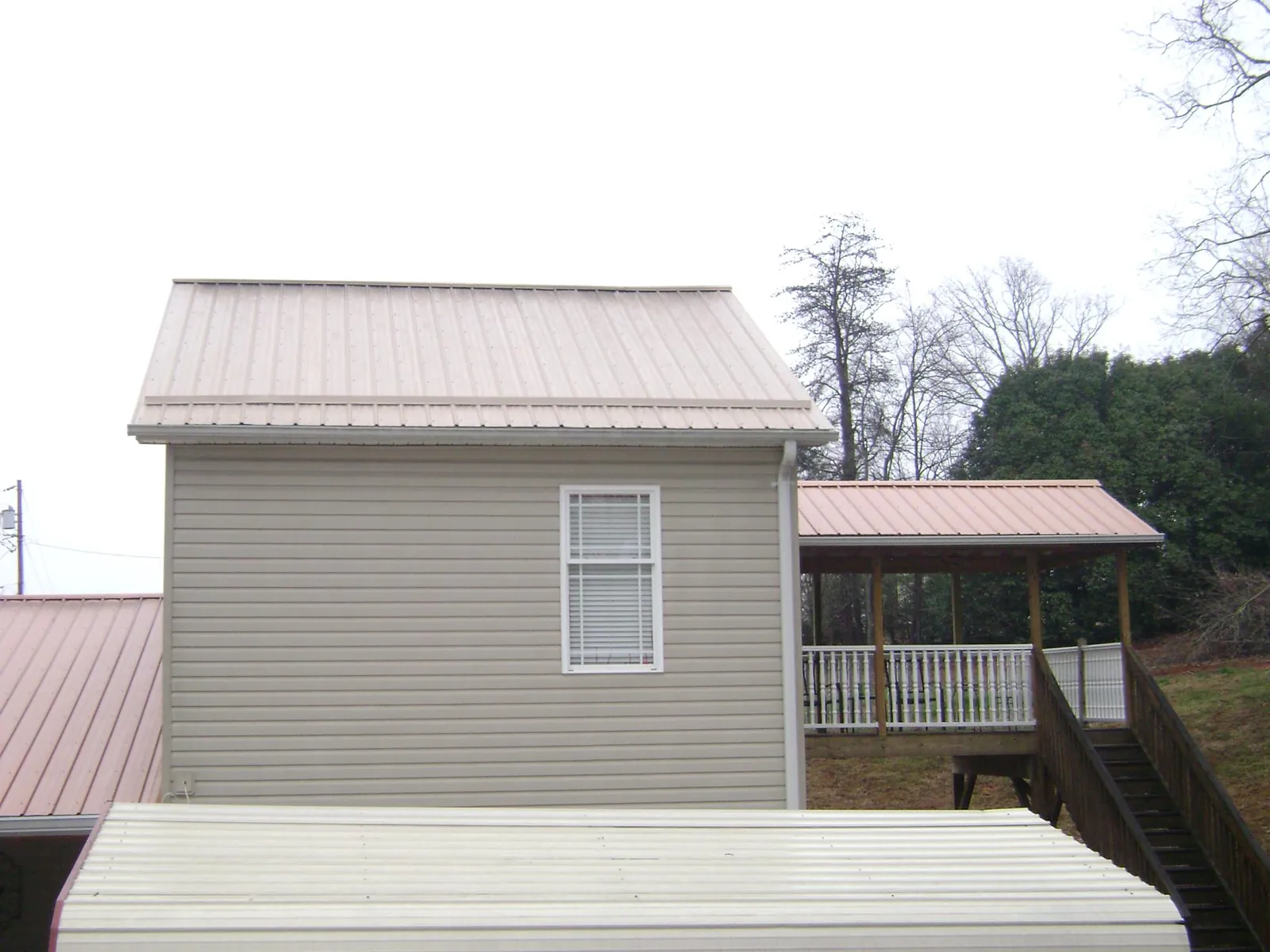 Tan metal roofs on a two story addition and attached porch, from a Roof Replacement job in Port Elizabeth