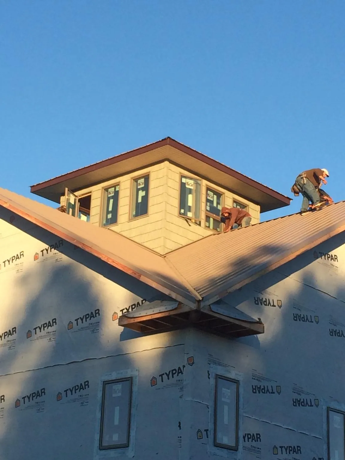 Roofers working around a rooftop cupola on a new metal roof at sunset — Roof Waterproofing in Port Elizabeth by Roofing Brothers